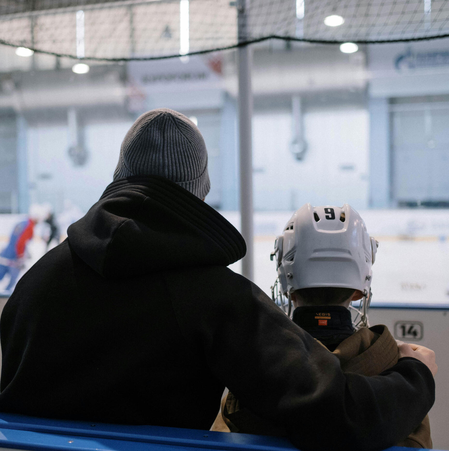 Hockey coach sits with a youth player in an arena. Photo by cottonbro studio via Pexels.